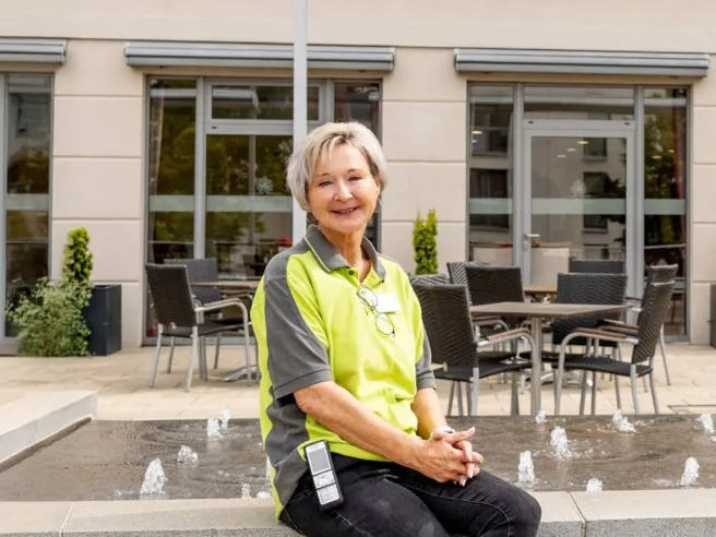 Pflegefachkraft bei PFLEGEN & WOHNEN Heimfeld im Außenbereich vor moderner Hausfassade.