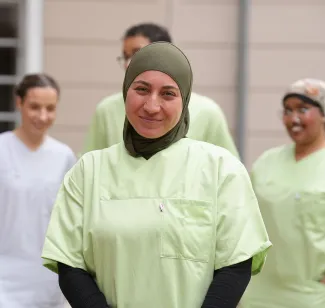 Im Vordergrund eine Pflegefachkraft mit Know-how bei PFLEGEN & WOHNEN HAMBURG, im Hintergrund Kollegen.