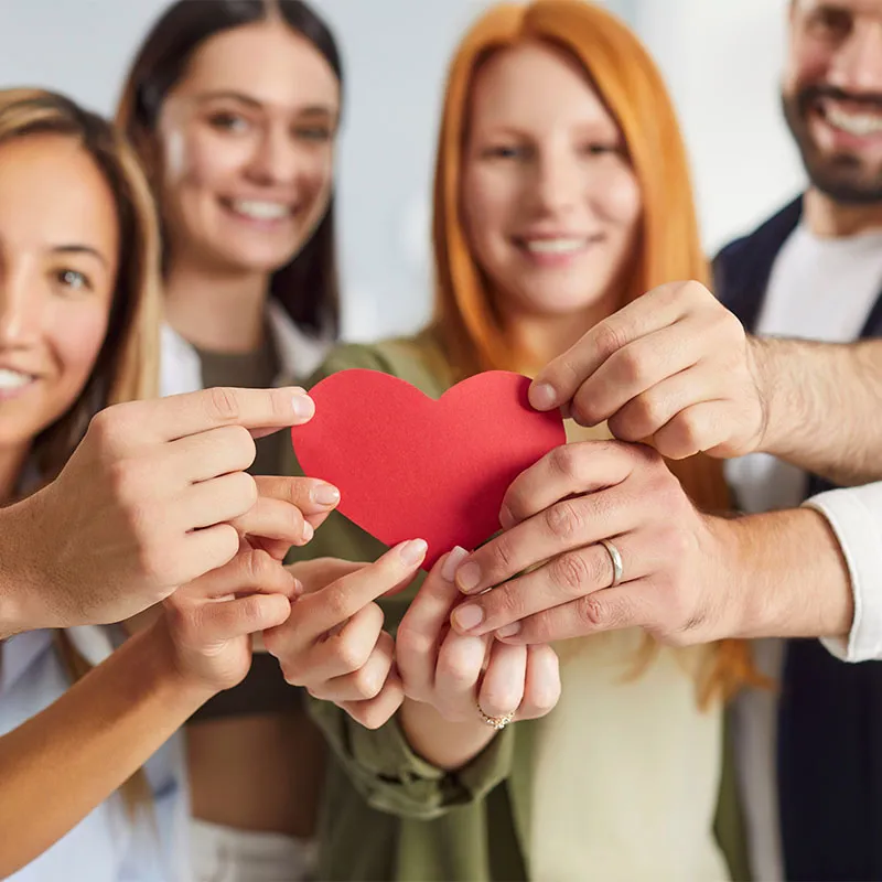 Mitarbeiter von PFLEGEN & WOHNEN HAMBURG halten ein rotes Herz als Symbol für die gemeinsame Philosophie.