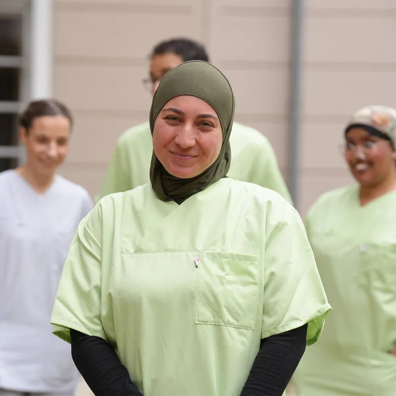 Im Vordergrund eine Pflegefachkraft mit Know-how bei PFLEGEN & WOHNEN HAMBURG, im Hintergrund Kollegen.